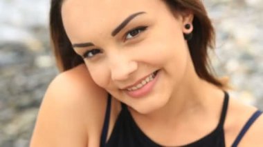 Kahverengi gözlü gülümseyen ve kameraya dalgalar deniz bir arka plan üzerinde seyir tatlı güzel genç esmer kız