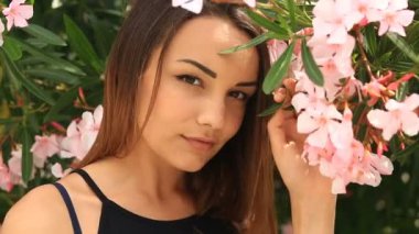 Şirin ve bir arka plan ağaç çiçek çiçek pembe kameraya bakarak gülümseyen güzel genç esmer