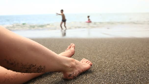 Pied femmes sur la plage à côté de la ligne de surf, vue sur la mer — Video