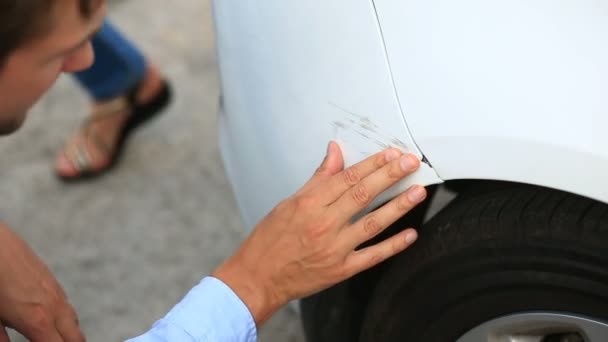 Guardando un veicolo danneggiato. uomo ispeziona i danni dell'auto dopo un incidente — Video Stock