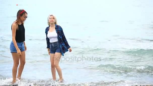 两个性格开朗可爱女友有乐趣上海滩站在海 — 图库视频影像