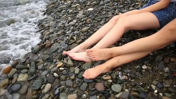 Twee mooie vriendinnen zijn zittend op het strand en praten — Stockvideo