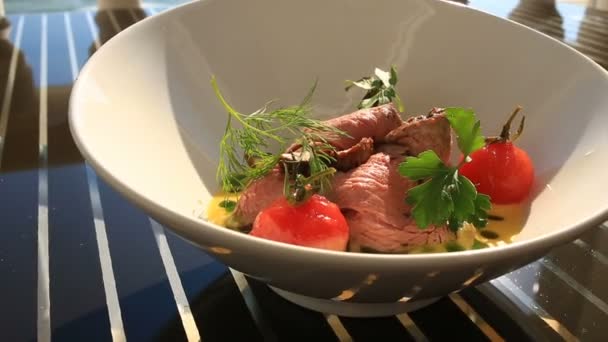 El jefe de cocina decora un plato de alta cocina con la ayuda de pinzas. Primer plano. Cerdo con verduras — Vídeo de stock