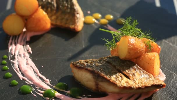 Un plato de alta cocina. Primer plano. Pescado con patatas jóvenes. salmonete. Con una copa de vino blanco. Restaurante Primorsik con vistas al mar . — Vídeo de stock