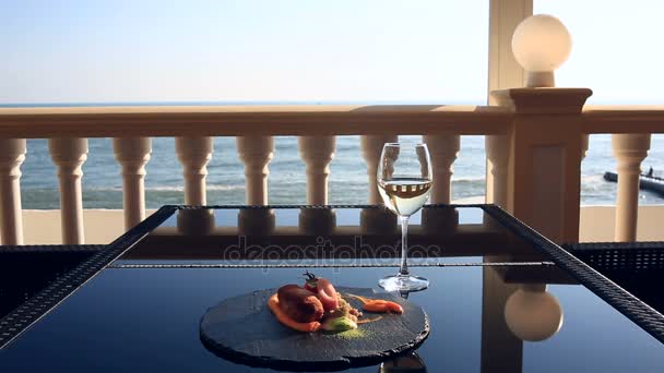 Gerichte im Gourmetrestaurant. Nahaufnahme. Schnitzel aus Kaninchenfleisch mit einer Garnitur aus grünem Buchweizen. ein Glas Weißwein. Restaurant am Meer mit Meerblick — Stockvideo