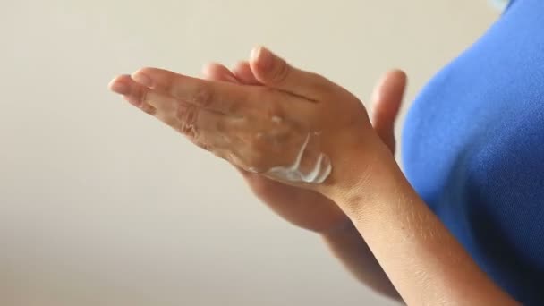 Donna sta cremando le mani per la cura della pelle morbida. Una donna si spalma le mani con una crema per le mani sullo sfondo del seno . — Video Stock