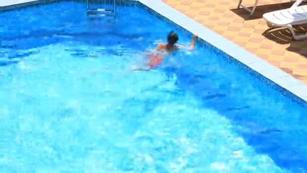 El niño está nadando en el agua azul de la piscina. vista desde arriba . — Vídeo de stock