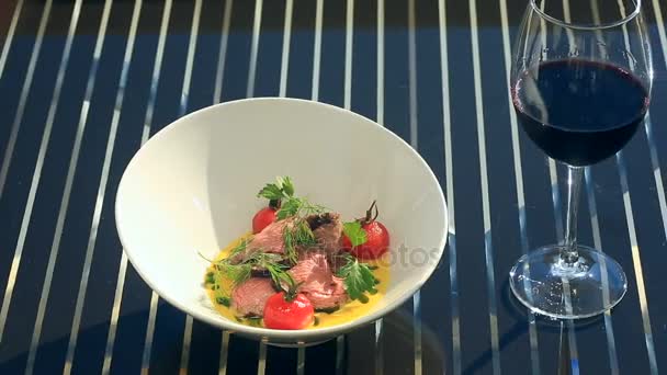 Un plato de un restaurante gourmet. Primer plano. Cerdo con verduras y una copa de vino tinto. Restaurante junto al mar — Vídeos de Stock