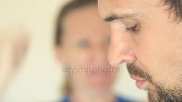 A mulher grita com o homem. O rosto de um homem no perfil é close-up, o rosto das mulheres é turvo . — Vídeo de Stock