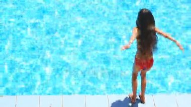 Çocuk havuz mavi su içinde yüzüyor. Yukarıdan görüntüleyin. Kız suya dalıyor
