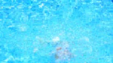 Çocuk havuz mavi su içinde yüzüyor. Yukarıdan görüntüleyin. Kız suya dalıyor
