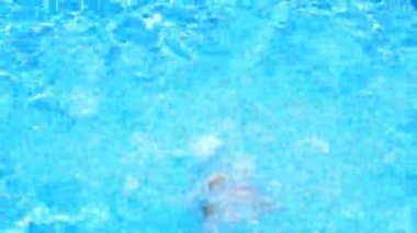 Çocuk havuz mavi su içinde yüzüyor. Yukarıdan görüntüleyin. Kız suya dalıyor