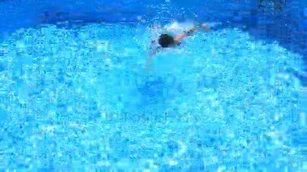 Het kind is zwemmen in het blauwe water van het zwembad. van bovenaf bekijken. — Stockvideo