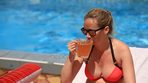 Dronken pot-bellied vrouw in bikini en zonnebril bier drinken bij het zwembad — Stockvideo