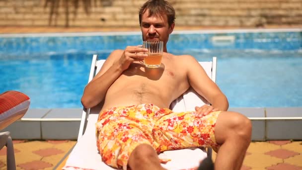 A drunk man in shorts drinking beer by the pool — Stock Video