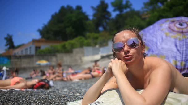 Femme bronzant sur la plage allongée sur des pierres — Video