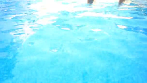 En man simmar under vattnet i en pool med blå vatten. Visa från ovan. — Stockvideo