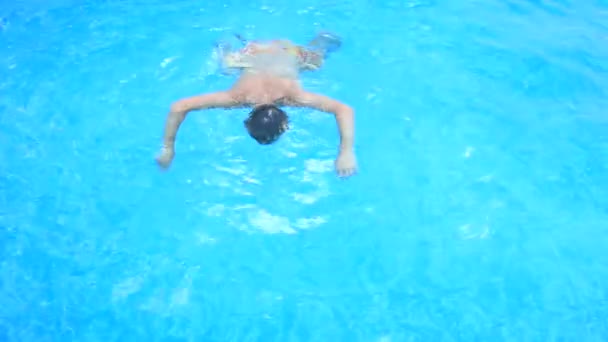 Um homem nada debaixo de água numa piscina com água azul. vista de cima . — Vídeo de Stock