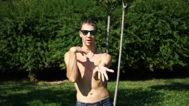 Ein junger glücklicher Kerl mit nacktem Oberkörper, der modernes Ballett tanzt und in einem Sommerpark herumturnt. Zeitlupe — Stockvideo