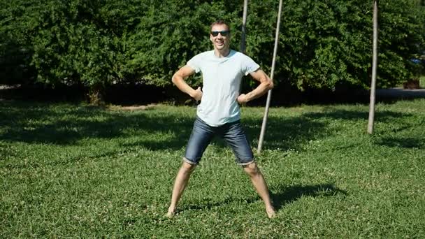 Een jonge gelukkige kerel moderne ballet en wacking dansen in een zomer-park. slow-mo — Stockvideo