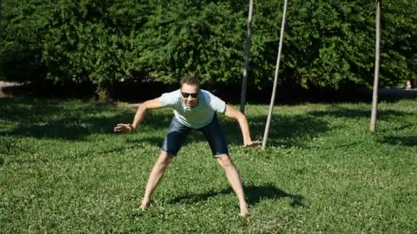 Молодий щасливий хлопець танцює сучасний балет і качається в літньому парку. повільний час — стокове відео