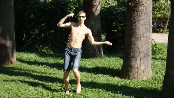Een jonge gelukkige kerel met een naakte torso moderne ballet en wacking dansen in een zomer-park. slow-mo — Stockvideo