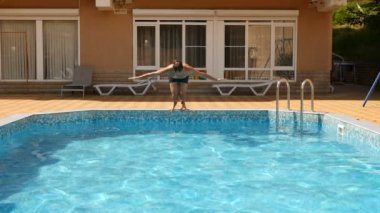 Bir adam mavi su ile havuz içine dalış. Su sıçramalarına farklı yönlere sinek. Ağır çekim