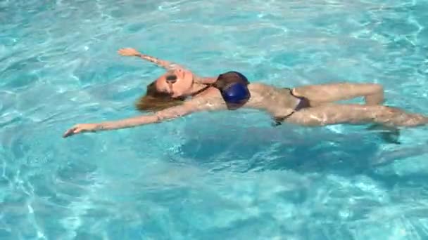 Hezká blondýnka se těší vody v bazénu. Pohled shora. Zpomalený pohyb . — Stock video