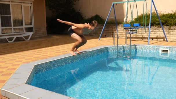 Człowiek nurkuje się w basenie z błękitną wodą. Odpryskami latają w różnych kierunkach. Zwolnionym tempie — Wideo stockowe