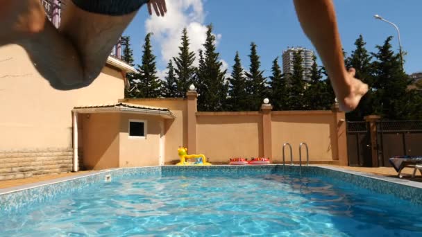 En man dyker in poolen med blått vatten. Stänk flyga i olika riktningar. Slow motion — Stockvideo