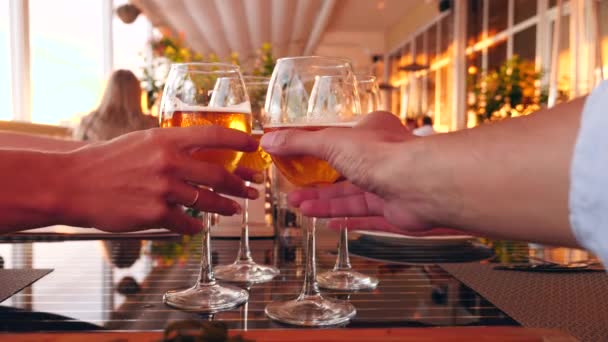 Amigos tintinean vasos con alcohol en un restaurante junto al mar. Primer plano. cámara lenta — Vídeo de stock