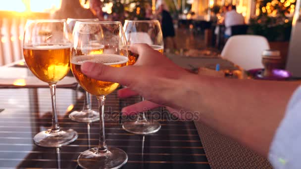 Amigos tintinean vasos con alcohol en un restaurante junto al mar. Primer plano. cámara lenta — Vídeo de stock