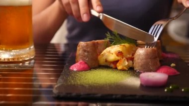 Sahil Restoran. Bir kadın et yiyor ve bir restoranda bira içiyor. Ağır çekim. yakın çekim