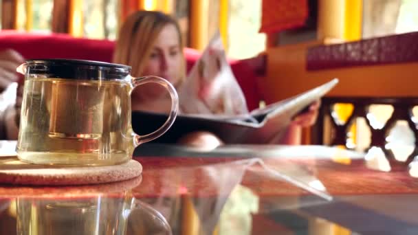 Chica bebe té y mira menú en un restaurante chino. Movimiento lento — Vídeo de stock