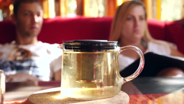 A couple is drinking tea and watching the menu in a Chinese restaurant. Slow motion — Stock Video
