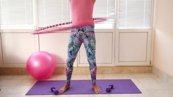 Um cara bonito brincalhão em uma camiseta rosa e leggings azuis está envolvido na aptidão retratando uma menina. Movimento lento — Vídeo de Stock