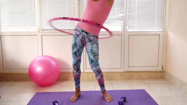 Een speelse knappe jongen in een roze T-shirt en blauwe legging is betrokken bij fitness beeltenis van een meisje. Slow motion — Stockvideo