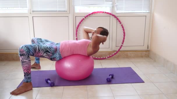 Een speelse knappe jongen in een roze T-shirt en blauwe legging is betrokken bij fitness beeltenis van een meisje. Slow motion — Stockvideo