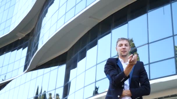 Een jonge gelukkig zakenman in een pak dansen moderne ballet en wacking tegen de achtergrond van een business center gebouw. Slow-mo — Stockvideo