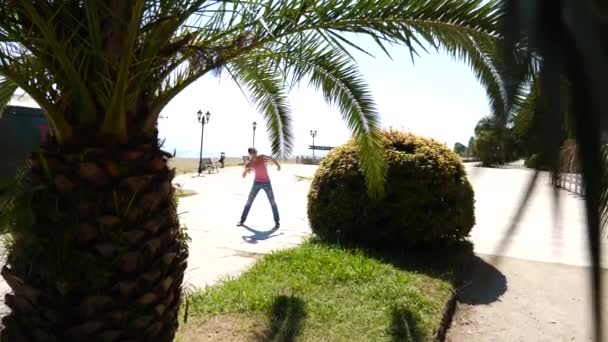 Um jovem feliz dançando balé moderno e batendo na orla marítima no fundo do mar. Devagar. — Vídeo de Stock