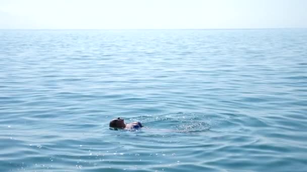 Mujer guapa rubia disfrutando del agua en el mar abierto, flotando. Vista desde arriba. Movimiento lento . — Vídeo de stock