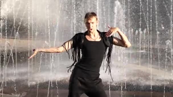 Een jonge gelukkige kerel moderne ballet en wacking dansen op een achtergrond van een fontein in een zomer-park. Slow-mo — Stockvideo