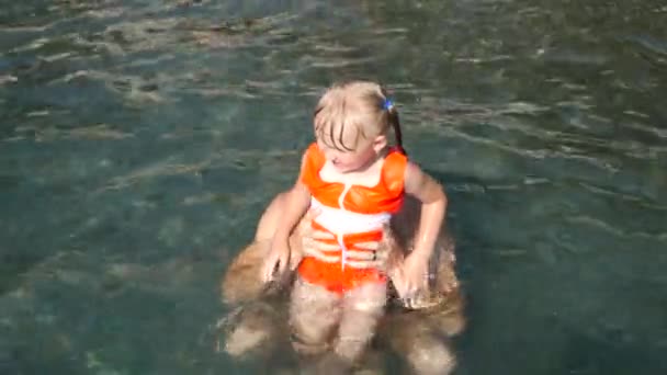 Papá juega con su pequeña hija linda de tres años en el mar. 4 k. Cámara lenta — Vídeos de Stock