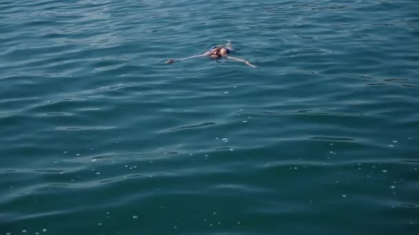 Jolie femme blonde profitant de l'eau en pleine mer, flottant. Vue d'en haut. Mouvement lent . — Video