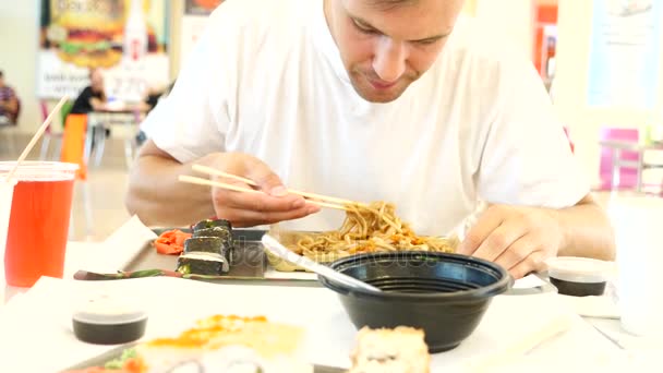 Um homem come comida chinesa num restaurante de fast food. 4K. Movimento lento . — Vídeo de Stock