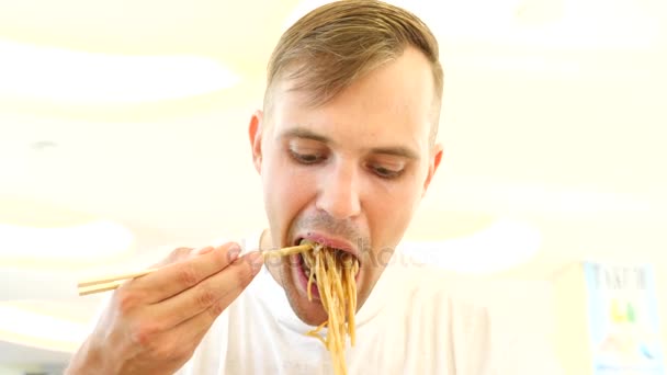 Um homem come comida chinesa num restaurante de fast food. 4K. Movimento lento . — Vídeo de Stock