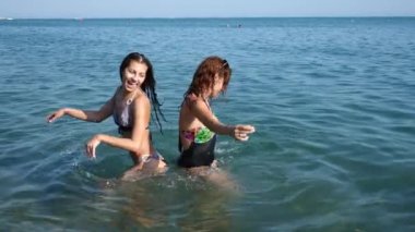 İki seksi kız arkadaşım, esmer ve Kızıl saçlı kendilerini denizin tadını çıkarıyor. Birbirlerine su ile serpin ve eğlenin. Ağır çekim. 4k.