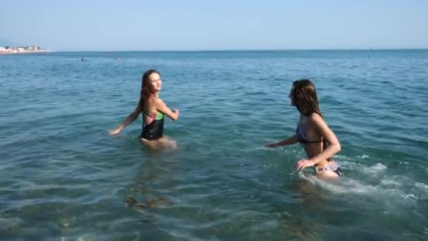 Twee sexy vriendinnen, brunette en de roodharige zijn zelf genieten in de zee. Strooi elkaar met water en veel plezier. Slow-motion. 4k. — Stockvideo