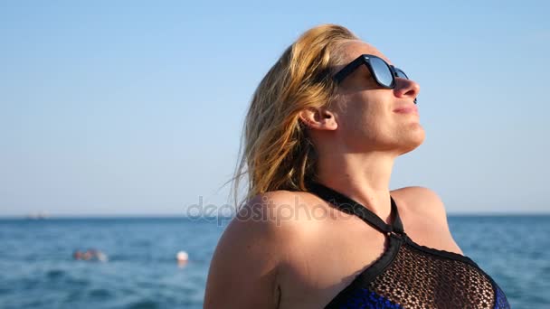 Chica sexy en bikini azul divirtiéndose tumbado en la playa en las olas, cámara lenta. 4K — Vídeo de stock