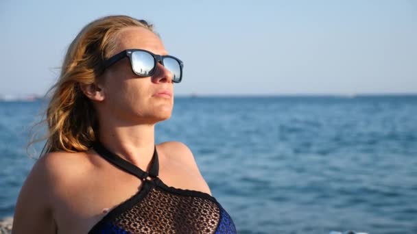 Ragazza sexy in bikini blu divertirsi sdraiato sulla spiaggia tra le onde, al rallentatore. 4K — Video Stock